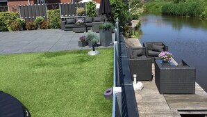 A patio with outdoor furniture and a view of a canal.