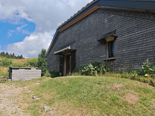 Un bâtiment rustique avec un toit en pente et une porte en bois.