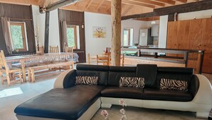 Een moderne woonkamer met een hoekbank, een glazen salontafel en een eethoek met houten meubels.