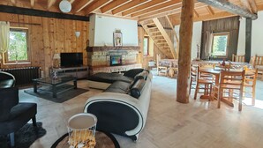 Een gezellig chaletinterieur met een woonkamer, een open haard, een eethoek en een trap.