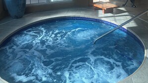 Ein Whirlpool mit Blick auf eine geflieste Wand und ein Fenster mit Milchglas.