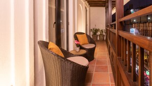 A balcony with wicker furniture, a small table with a vase of flowers, and potted plants. - Hotel Roadhouse, Thamel, Kathmandu- Contemporary Boutique (Kathmandu)