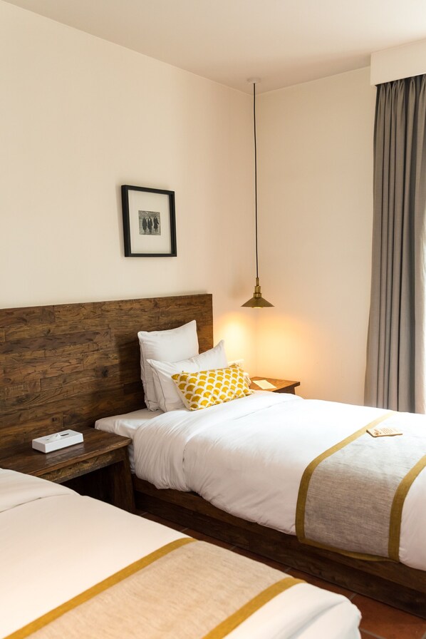 A hotel room with a wooden headboard, a bed with white bedding and a yellow pillow, a bedside table with a lamp, and a framed picture on the wall. - Hotel Roadhouse, Thamel, Kathmandu- Contemporary Boutique (Kathmandu)