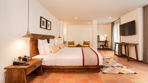 A hotel room with a large bed, bedside tables, a desk, a chair, a television, and a patterned rug. - Hotel Roadhouse, Thamel, Kathmandu- Contemporary Boutique (Kathmandu)