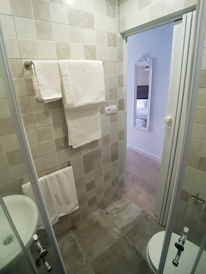 A bathroom with two sinks, a shower, and a toilet. There are towels hanging on the wall. - Hostal Puente de Hierro (Logroño)
