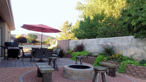 Eine Außenpatio-Terrasse mit Grill, Sitzgelegenheiten und einem Feuerkorb.