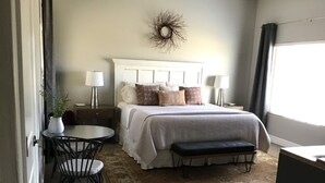 Ein Schlafzimmer mit Bett, Nachttischen, Schreibtisch, Stühlen, Teppich und einem Fenster.