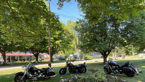 Three motorcycles parked in a grassy area with trees and a flower bed in the foreground. - FISHING AND FAMILY FRIENDLY- NOTHING FANCY (Linesville)