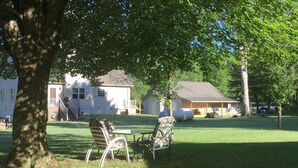 A grassy yard with two chairs and a table, a house in the background, and a tree in the foreground. - FISHING AND FAMILY FRIENDLY- NOTHING FANCY (Linesville)
