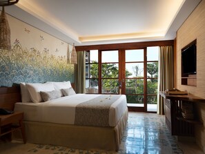 Une chambre d’hôtel avec un grand lit, une télévision et une vue sur la verdure par les fenêtres.