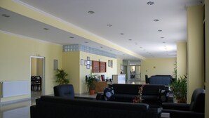 A hotel lobby with a reception desk, seating area, and a staircase leading to an upper level. - Ustundag Otel (Keçiborlu)