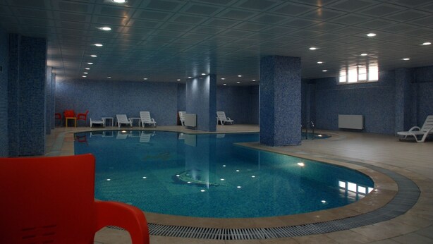 An indoor swimming pool with tiled walls and ceiling, surrounded by lounge chairs. - Ustundag Otel (Keçiborlu)