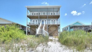 Ein mehrstöckiges Gebäude direkt am Strand, mit einer Treppe zum Eingang.
