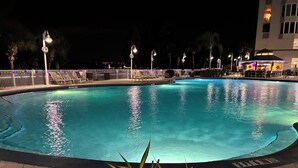 Una piscina nocturna con un bordeado de azulejos y un cartel que indica la profundidad.