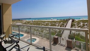 Un balcon avec une piscine, une vue sur la plage et une jetée visible au loin.