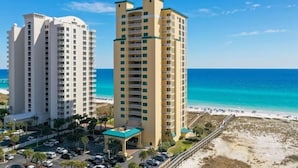 Deux immeubles de grande hauteur dotés de balcons, un espace de stationnement et une vue sur la plage.