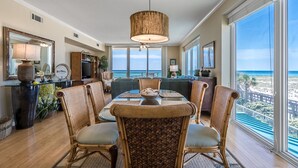 Un salon spacieux avec une grande table à manger, des chaises en osier et une vue sur l’océan.