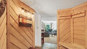 Un corridoio interno in legno che conduce a una zona giorno con un divano e una televisione.