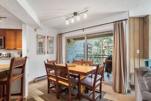 A dining area with a wooden table and chairs, a kitchen with wooden cabinets, and a view of the outdoors through a sliding glass door. - 2br 2ba Condo, newly remodeled - 200yds to Lift - 2 Blocks to Downtown (Breckenridge)
