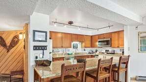 Una cucina moderna con mobili in legno, un piano di lavoro in granito e un forno a microonde integrato.