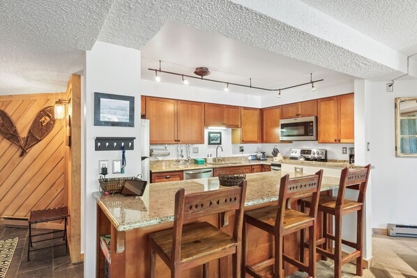 A modern kitchen with wooden cabinets, a granite countertop, and a built-in microwave. - 2br 2ba Condo, newly remodeled - 200yds to Lift - 2 Blocks to Downtown (Breckenridge)