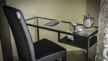 A small, modern room with a glass table, a black leather chair, and a decorative tea set.