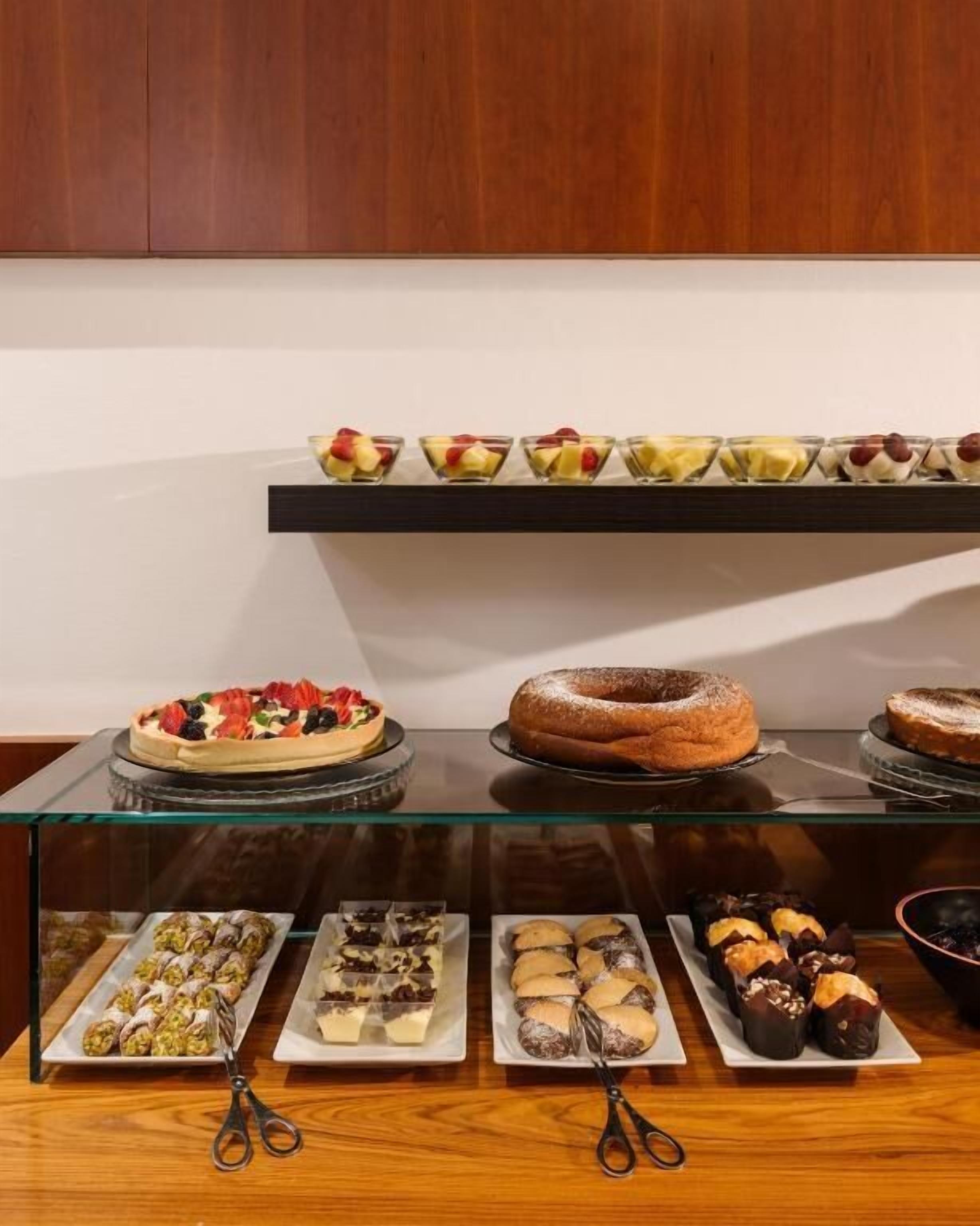 Una presentación de postres con diversas pastelerías y dulces en estantes de vidrio.