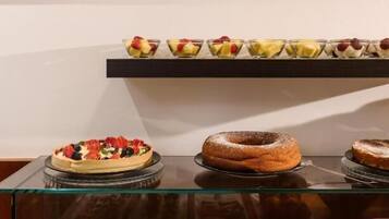 Una presentación de postres con diversas pastelerías y dulces en estantes de vidrio.