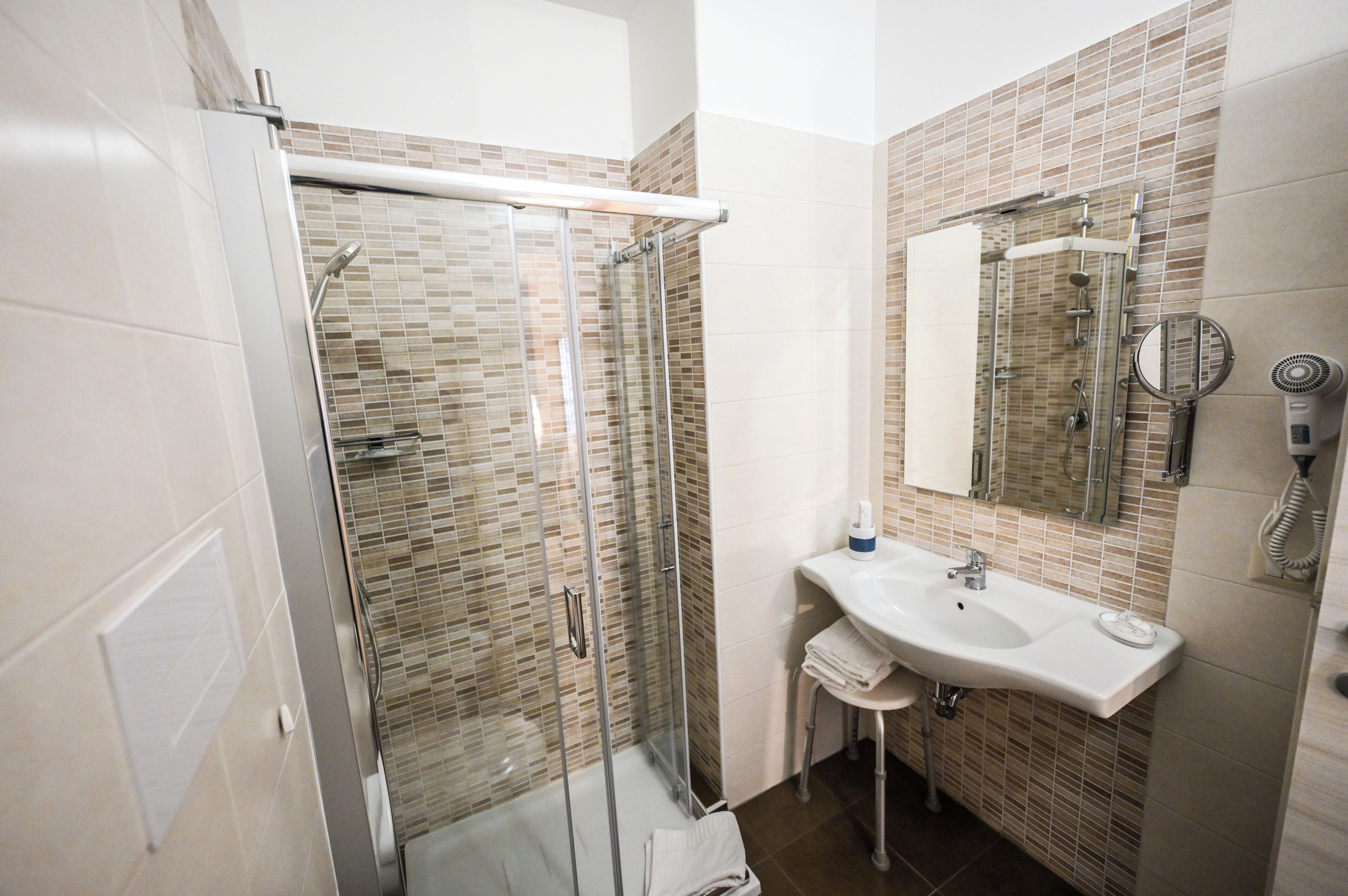 A bathroom with a glass-enclosed shower, a sink with a mirror, and a towel rack.