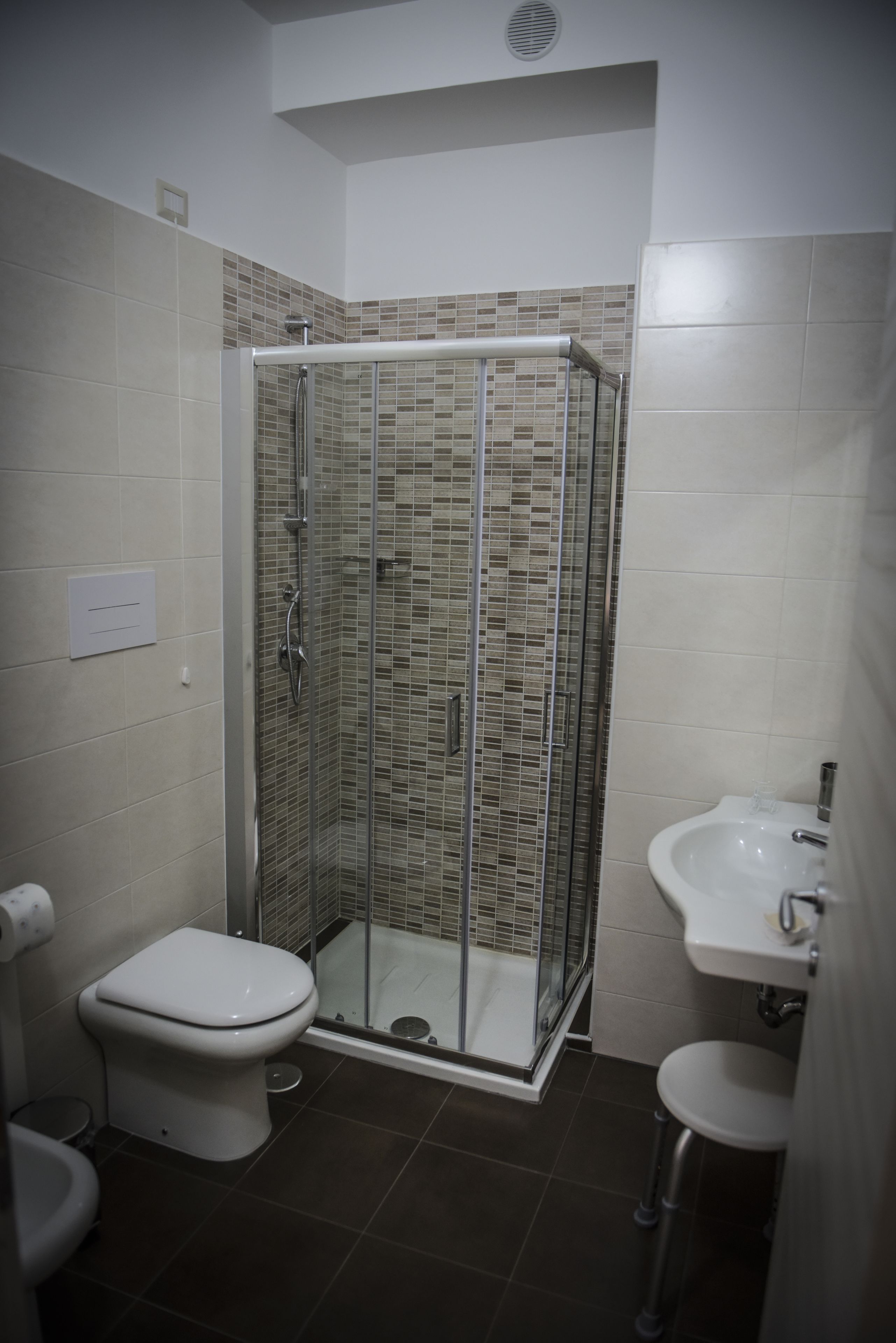 A bathroom with a glass-enclosed shower, a toilet, and a sink.