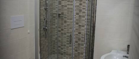 A bathroom with a glass-enclosed shower, a toilet, and a sink.