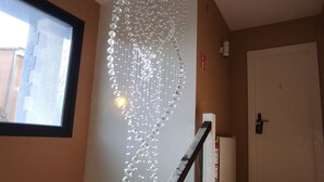 A hallway with a decorative light fixture, a window, and a door. - Los Patios de Santander (Santander)