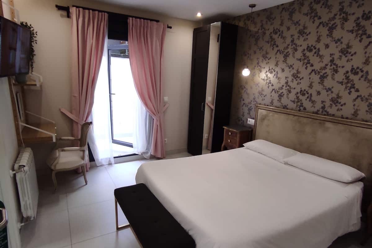 Ein Schlafzimmer mit einem großen Bett, einer Bank, einem Sessel, einem Schreibtisch und einer Heizung.