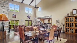 A spacious dining area with a large wooden table, leather chairs, and a stone fireplace. - FALL FLASH SALE-Perfect Getaway with Natural Spring Swimming Hole! (Spicewood)