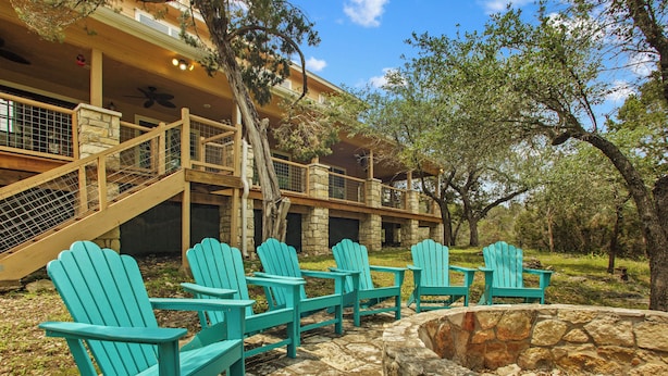 A stone patio with four turquoise Adirondack chairs and a stone fire pit. - FALL FLASH SALE-Perfect Getaway with Natural Spring Swimming Hole! (Spicewood)