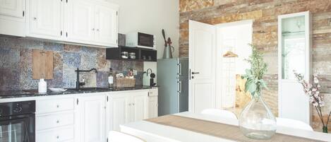 A modern kitchen with white cabinets, a built-in microwave, and a refrigerator.