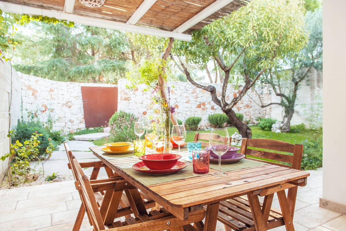 A wooden table set outdoors with various dishes and glasses.