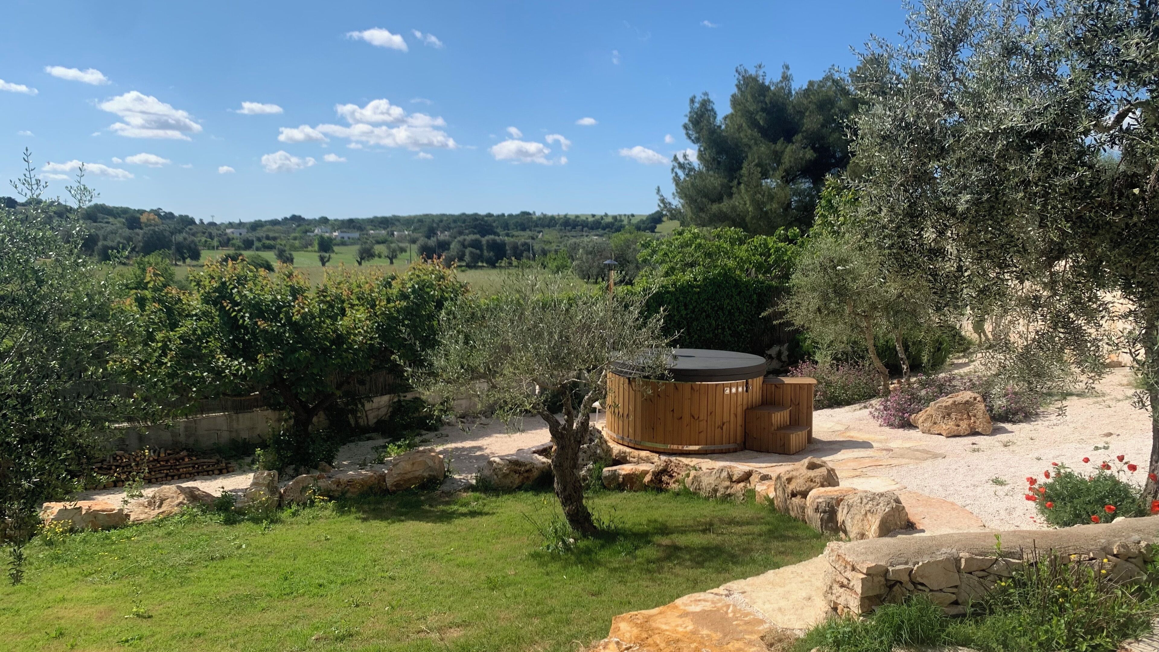 Un bain à remous dans un jardin planté d’oliviers, avec vue sur la campagne.