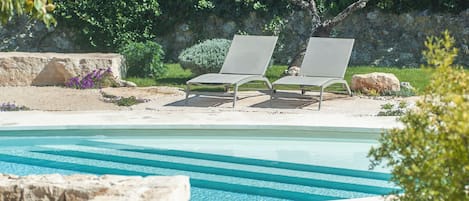 Una piscina al aire libre, tumbonas