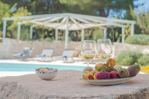 A dining table with a plate of food and two wine glasses, a bowl, and a white umbrella structure in the background. - Dimora il Mandorlo (Ostuni)