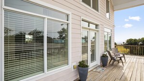 Una terraza de madera con dos sillas Adirondack y una planta en maceta.