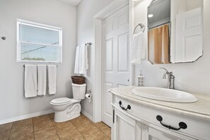 A bathroom with a toilet, sink, and window with blinds.