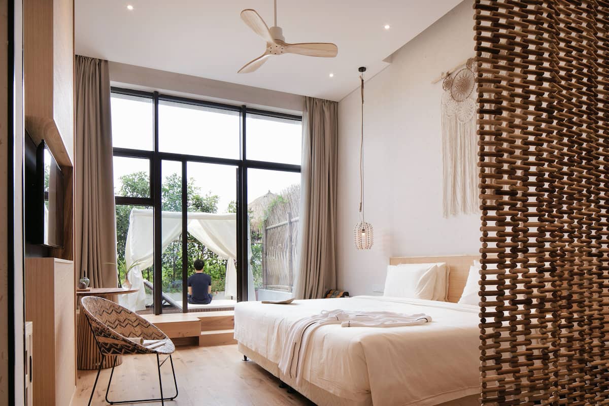 Un dormitorio moderno con una cama grande, un ventilador de techo y vistas al exterior.