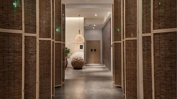 A hallway with wooden paneling on the walls, a round seating area, and a hanging light fixture.