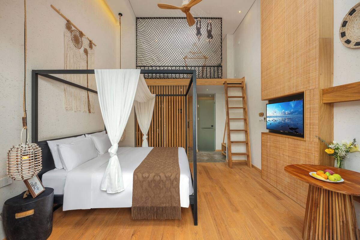 Un dormitorio moderno con cama, televisor, mesa de madera con fruta y balcón con vistas.