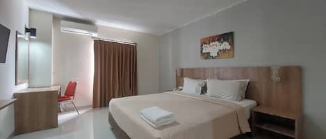 Une chambre d’hôtel avec un lit, un bureau, une chaise et un tableau au mur.