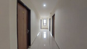 A corridor with doors on both sides, a tiled floor, and a ceiling light. - Kanasha Islami (Medan)
