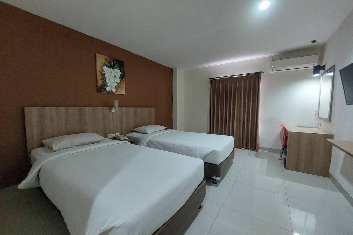 Habitación de hotel con dos camas, un escritorio, un espejo y un cuadro en la pared.