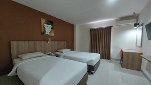 A hotel room with two beds, a desk, a mirror, and a painting on the wall. - Kanasha Islami (Medan)