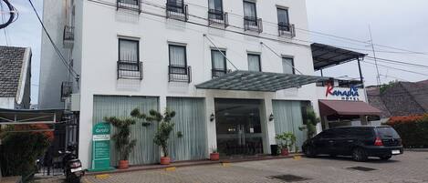 A hotel with a white facade, multiple balconies, and a covered entrance.